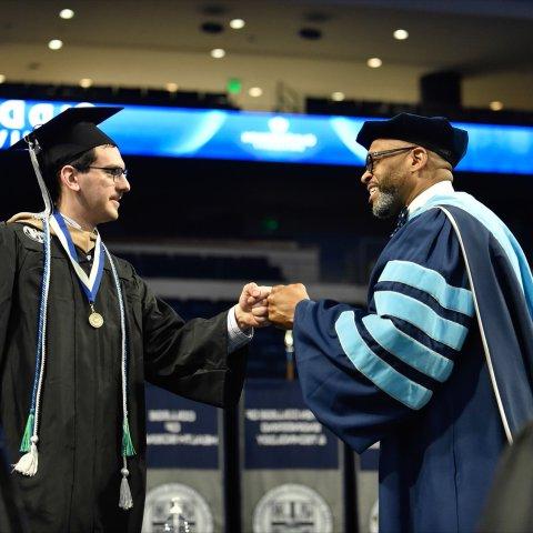 ODU President Brian Hemphill congratulates a Strome business graduate during commencement cermony